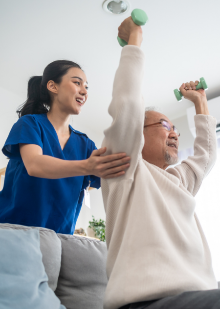 nurse helping senior man lift weights in home